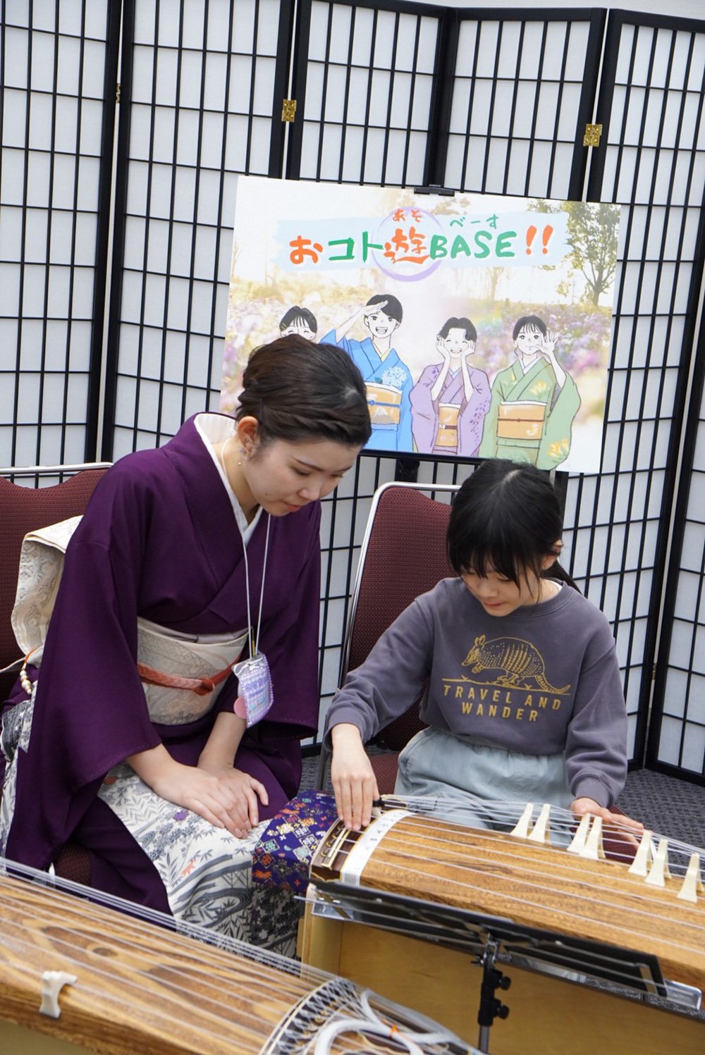 フォトスポットで箏奏者に指導を受けながら演奏体験する子ども