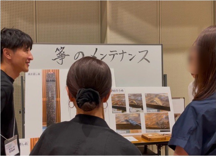 箏のメンテナンスの工程を解説するスタッフと来場者